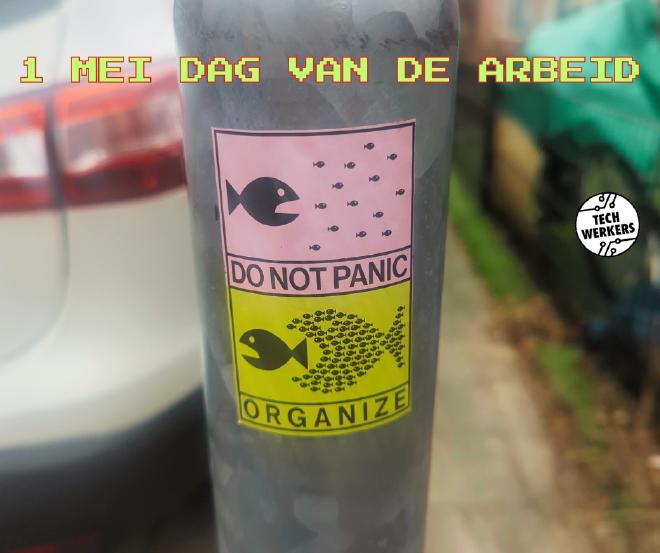 Klever op een lantaarnpaal met daarop in twee scènes. Scène 1: een grote vis probeert een hele school kleine vissen op te eten. Scène 2: de school kleine vissen spant samen en doet die ene grote vis vluchten. Bijschrift (in het Engels): Geen paniek, organiseer je.